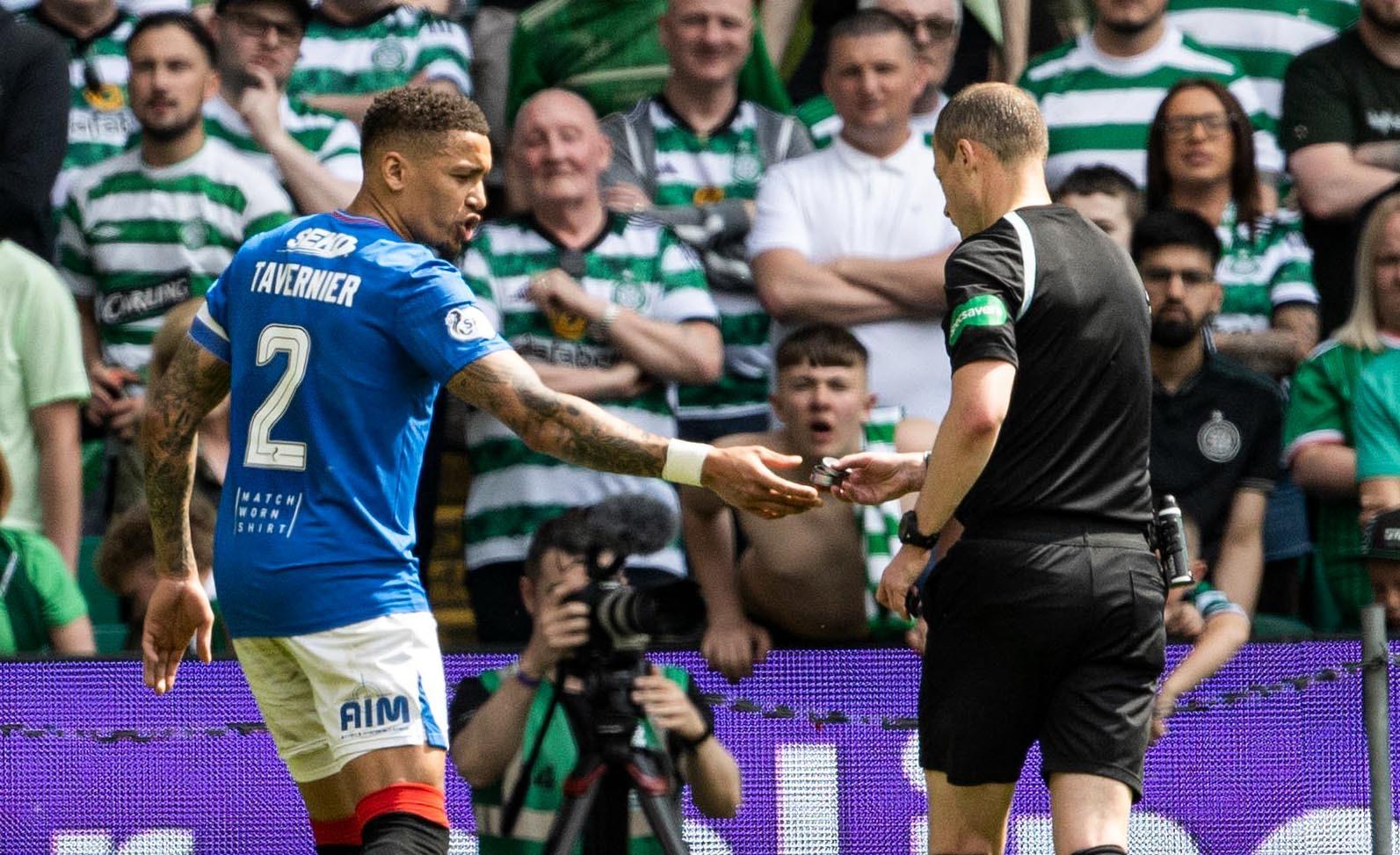 Rangers' James Tavernier hands referee Willie Collum an object that was thrown onto the pitch during a cinch Premiership match between Celtic and Rangers at Celtic Park.