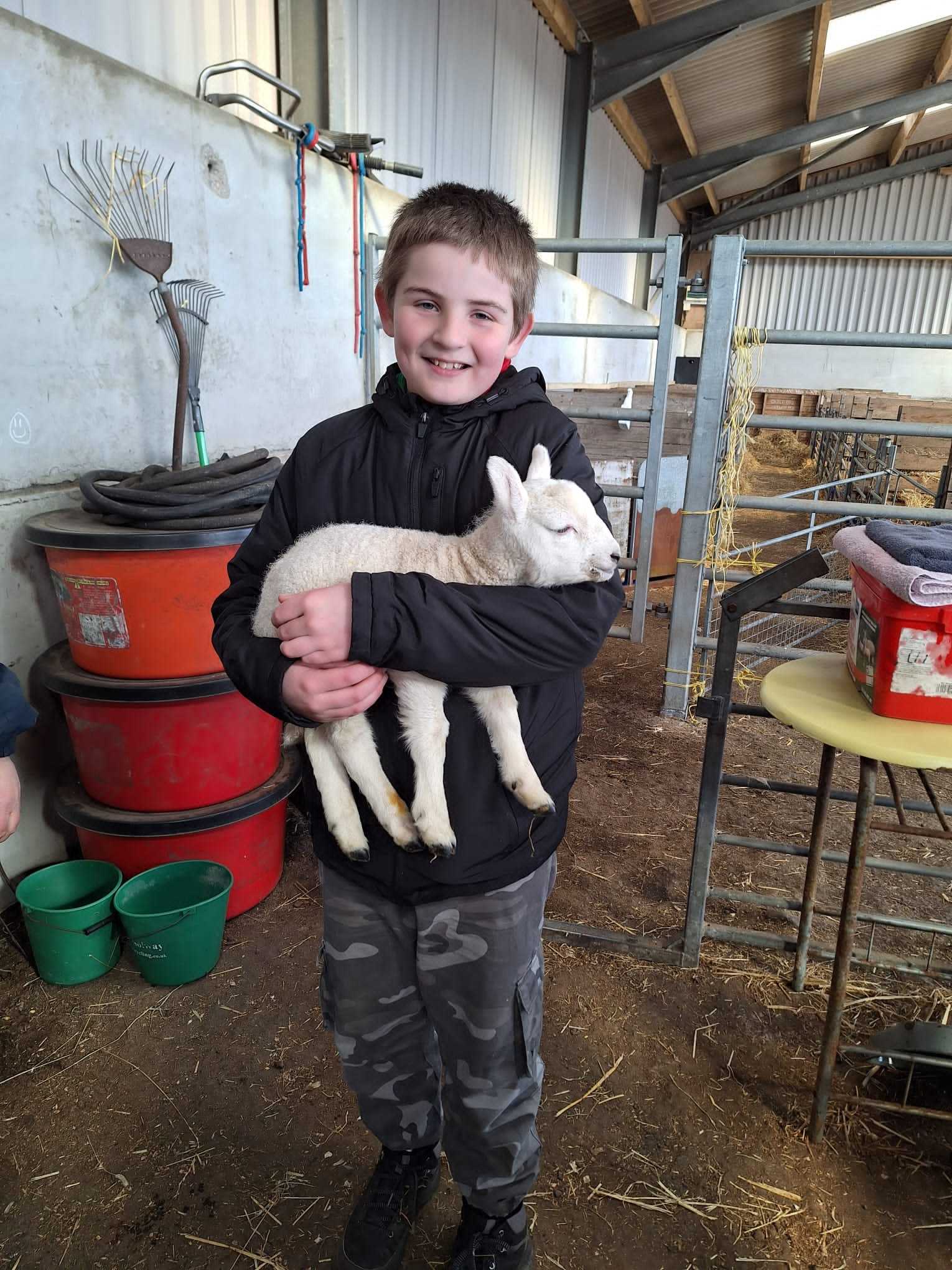Kyle holds a baby lamb as part of work to gain one of his many badges (family handout/PA). 