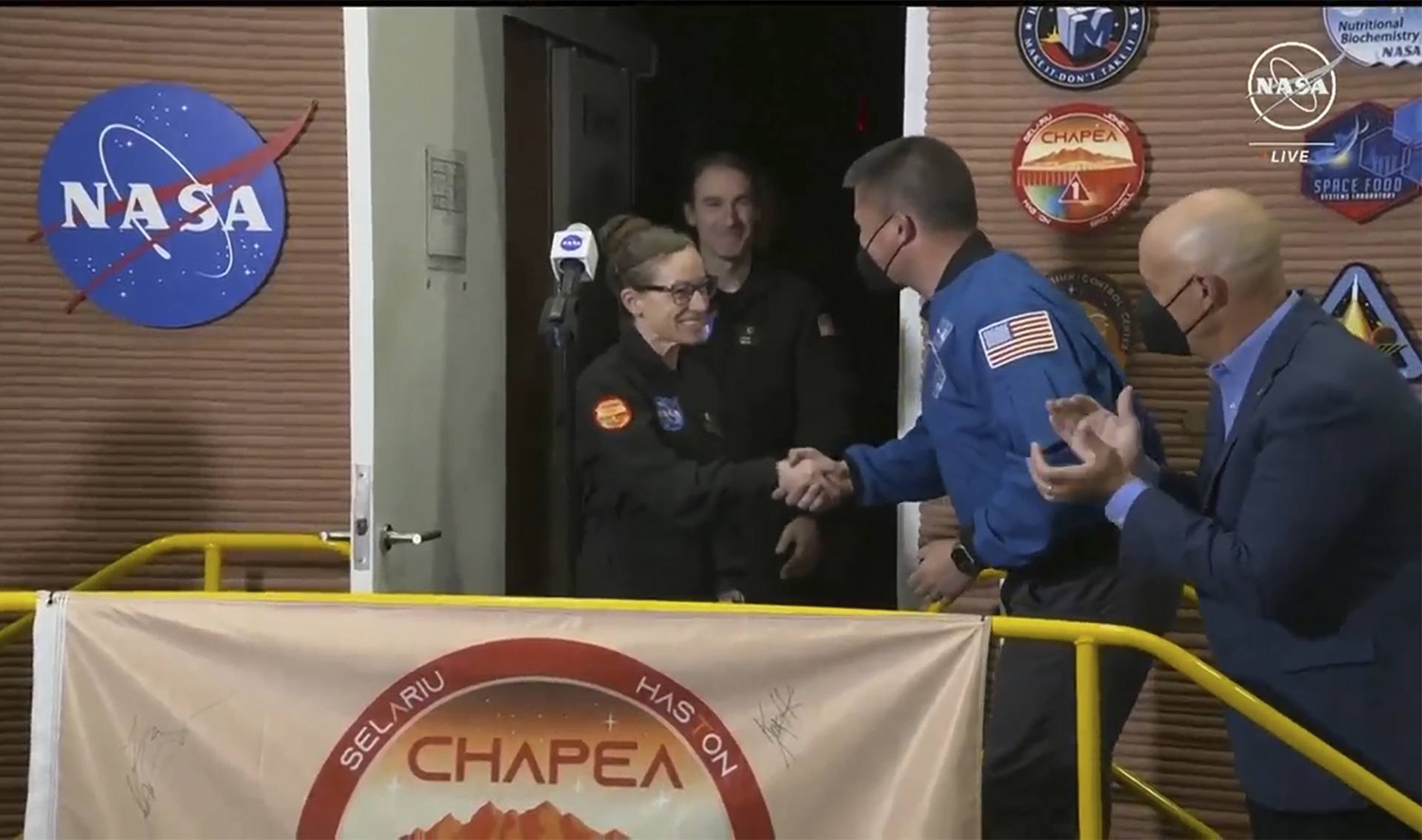 Kelly Haston, centre, shakes hands with Nasa deputy director flight missions Kjell Lindgren, second right, as other crew members emerge from their habitat (Nasa via AP)