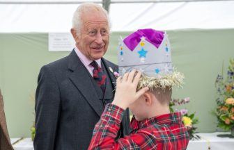 Schoolboy tries on prize-winning cardboard crown in front of the King