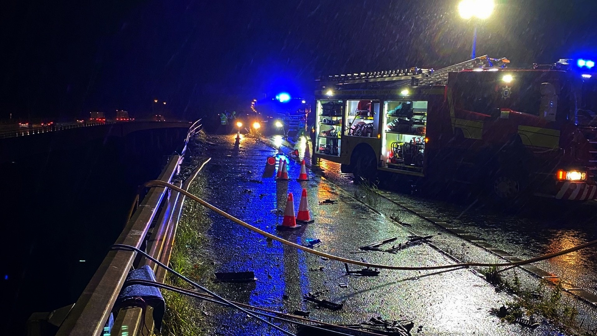 Cheshire Fire and Rescue Service and other emergency services on the scene under a bridge on the M6 in Cheshire where a lorry fell 60 metres from the Thelwall Viaduct between junctions 20 and 21, landing on the embankment below.