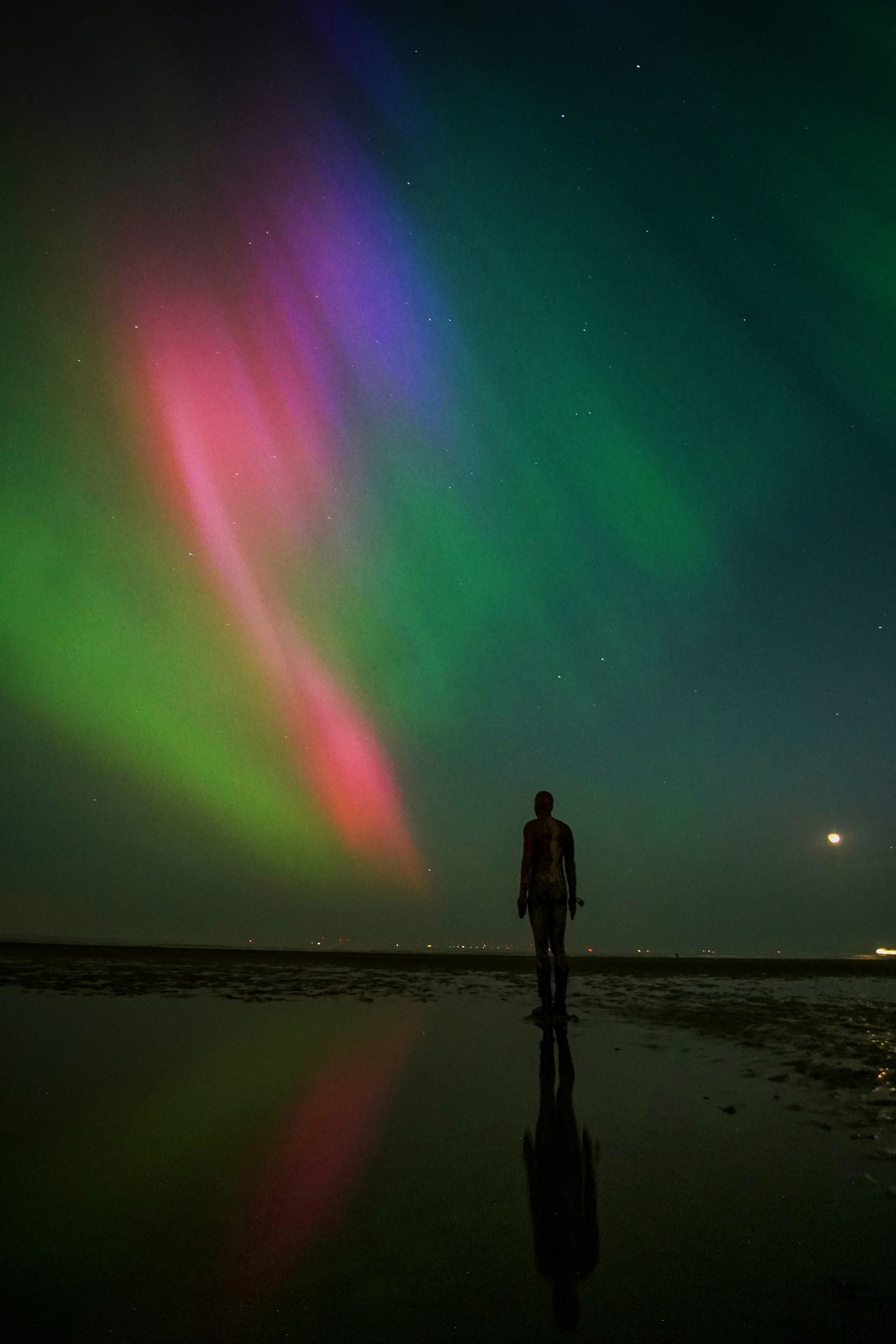 The Northern lights glow on the horizon above sculptures on Crosby Beach, Merseyside (Peter Byrne/PA) 