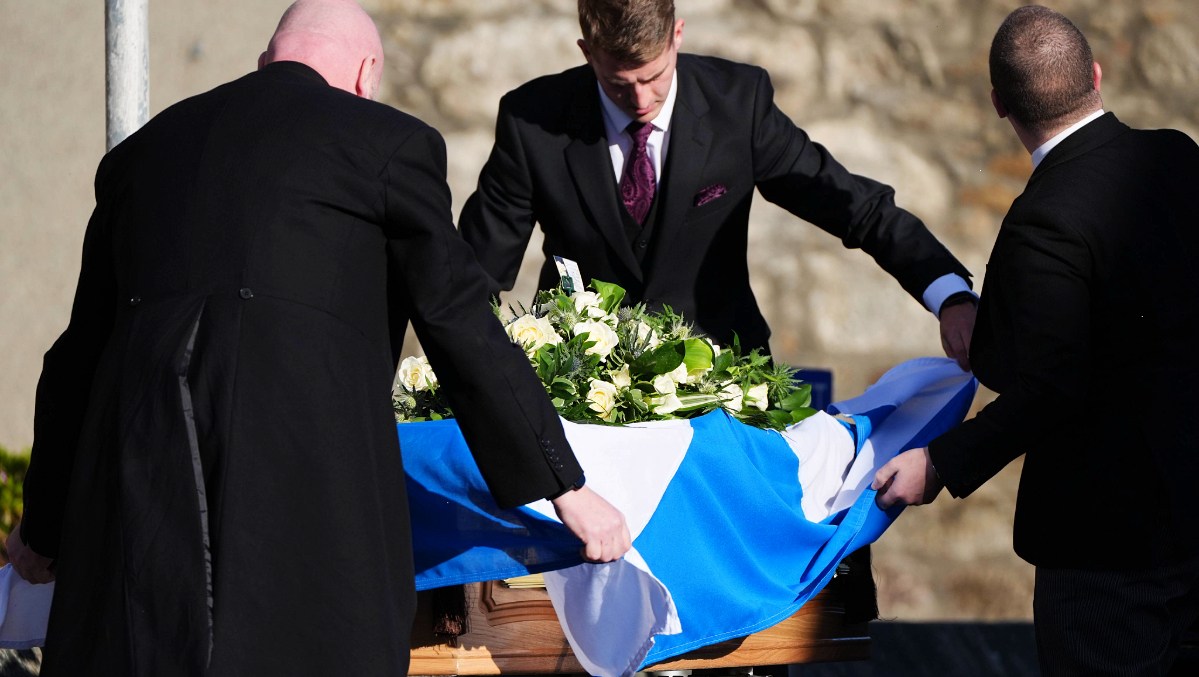 Pall bearers drape a Saltire flag over the coffin as it arrives at the funeral service for former first minister of Scotland Alex Salmond, at Strichen Parish Church.