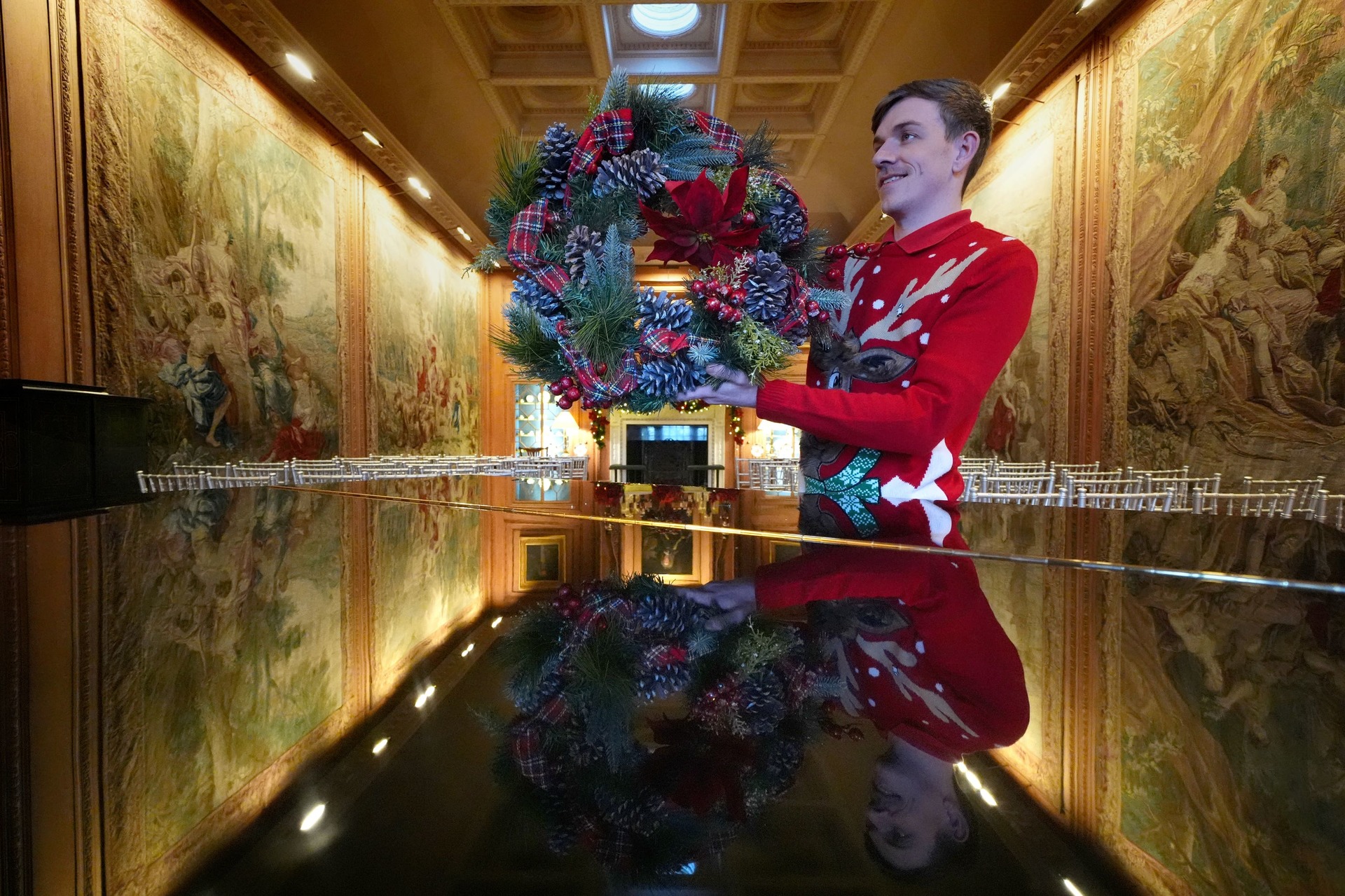 A steward prepares to hang a wreath in the tapestry room as finishing touches are made to Christmas decorations at Dumfries House (Andrew Milligan/PA). 