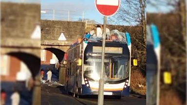 Roof of double-decker bus torn off after crashing into bridge