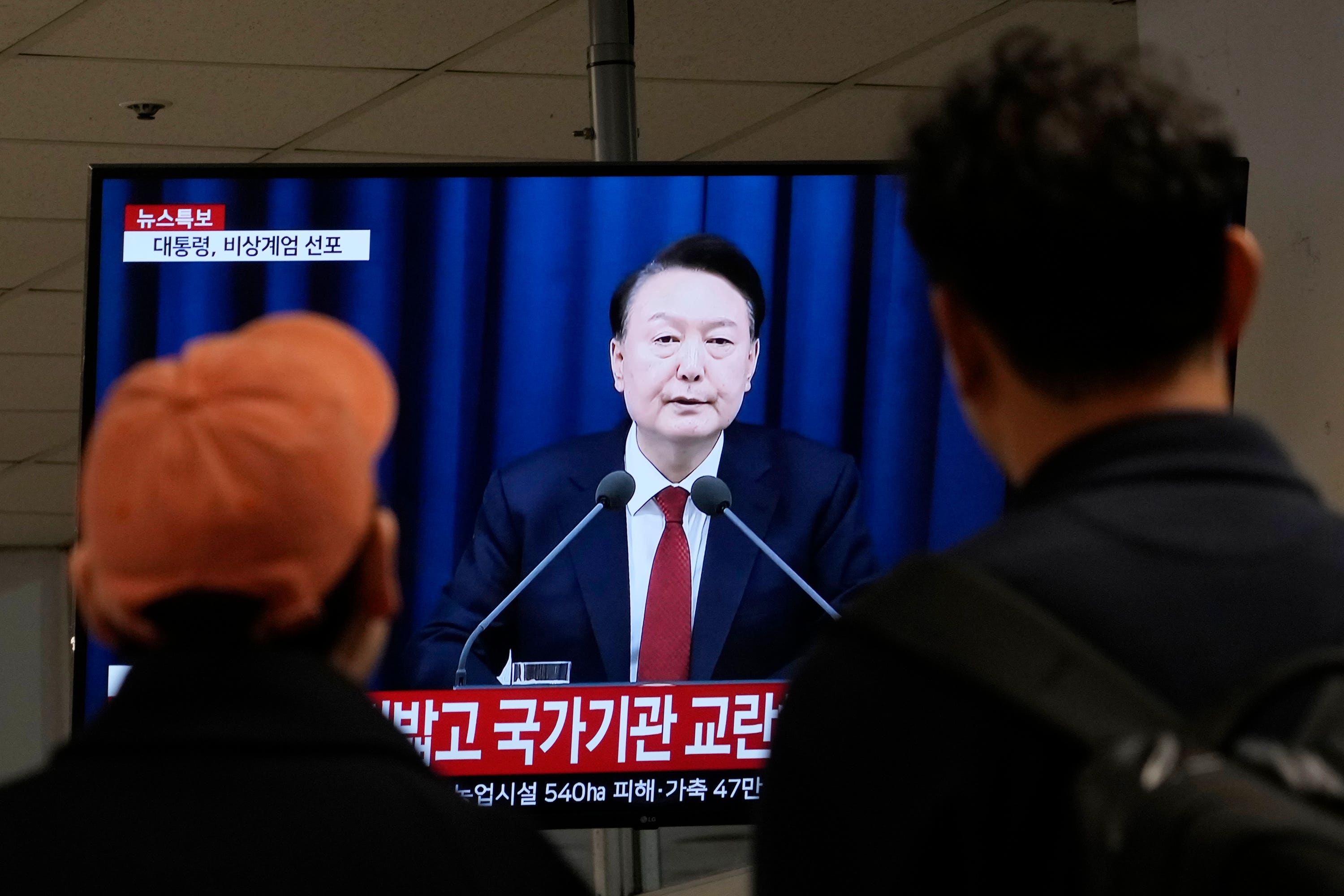 People at a bus terminal in Seoul watch a TV screen showing South Korean President Yoon Suk Yeol’s televised briefing (Ahn Young-joon/AP)