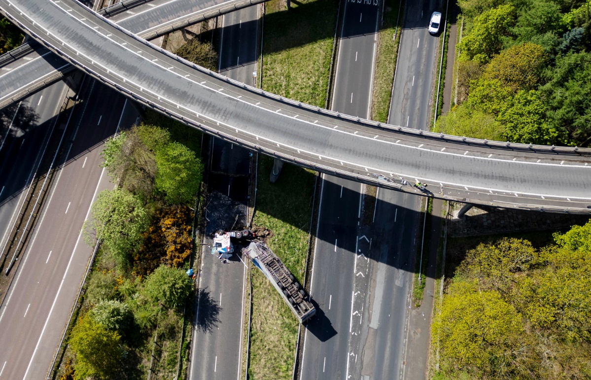 An HGV lorry is seen on its side after crashing through a barrier and falling from a bridge on the M90 near Perth.