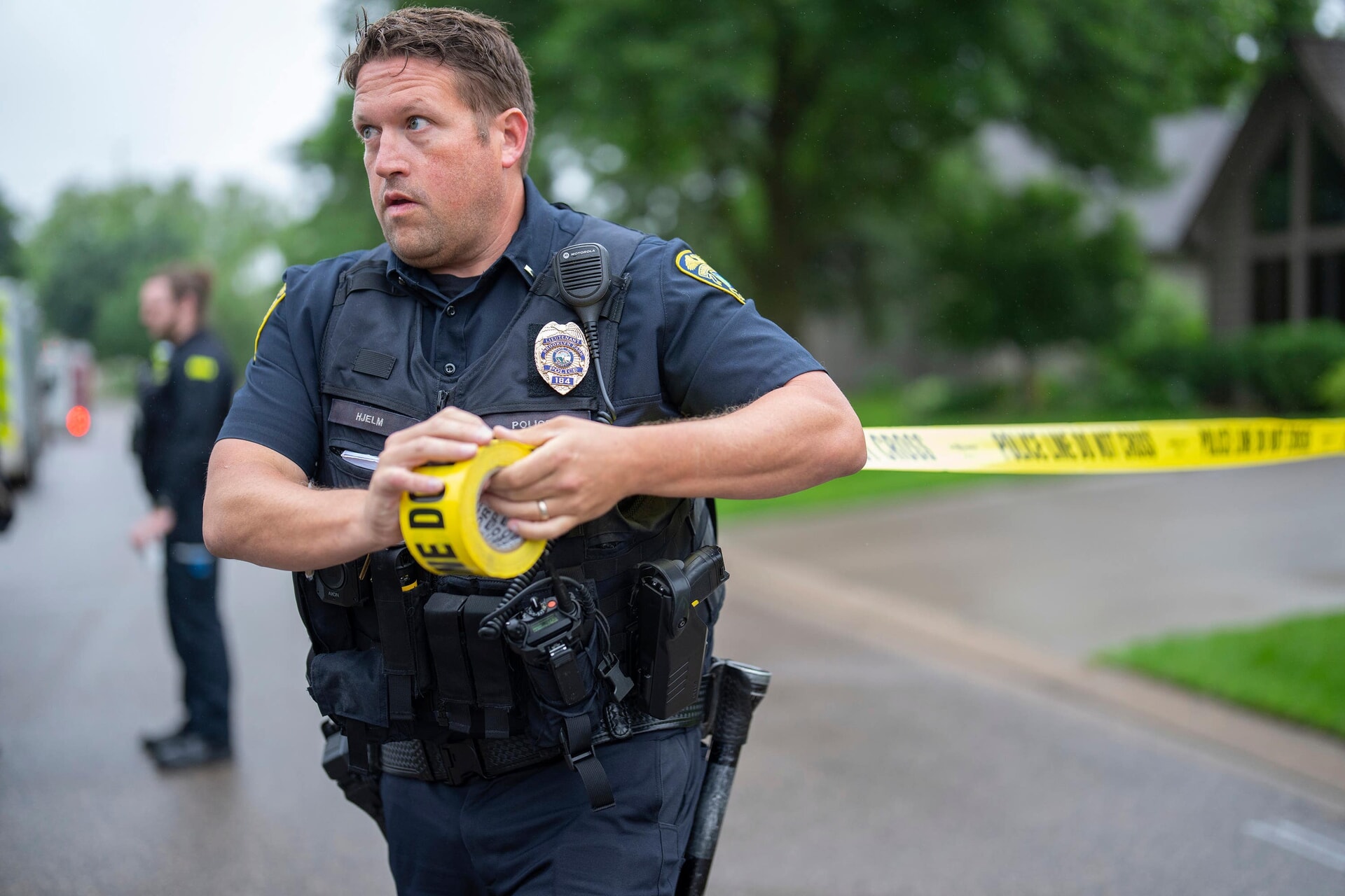 A police officer sets up a perimeter with police tape near the scene of the shooting.