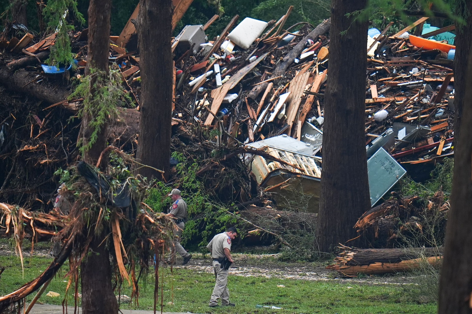Officials comb through the banks of the Guadalupe River after a flash flood swept through the area (Julio Cortez/AP)