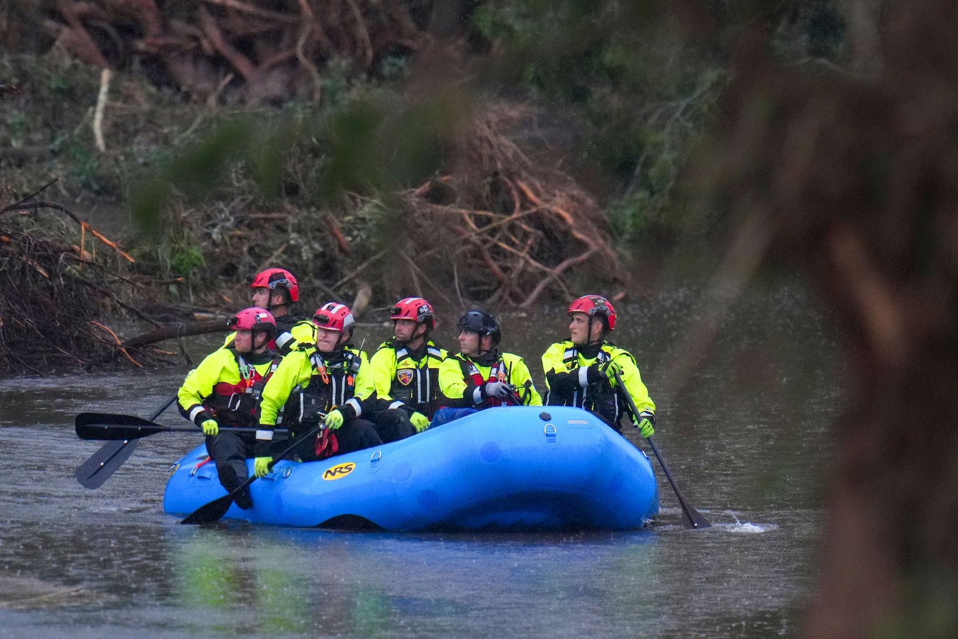 Officials ride a boat as they arrive to assist with a recovery effort at Camp Mystic in Hunt, Texas.