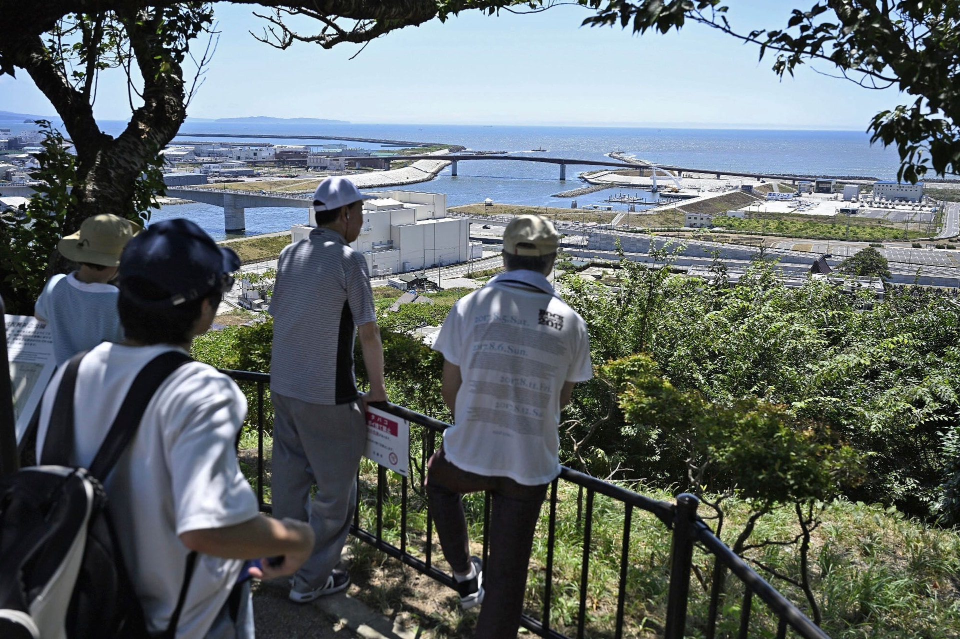 People who evacuated to Hiyoriyama mountain watch toward the sea in Ishinomaki, Miyagi prefecture, northern Japan (Muneyoshi Someya/Kyodo News/AP).