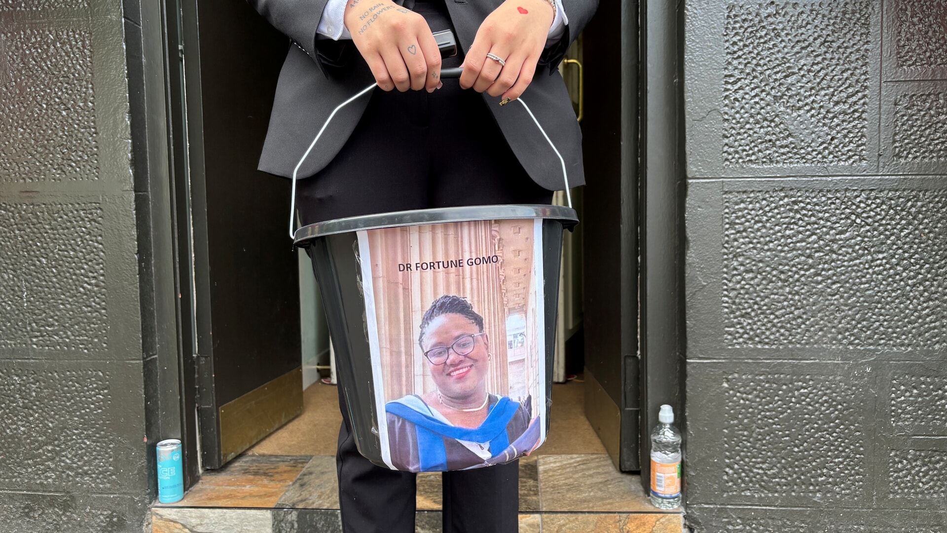 A members of a Dundee community holds a collection bucket outside Sandy's Bar in Dundee, close to where scientist Dr Fortune Gomo, 39, was fatally attacked