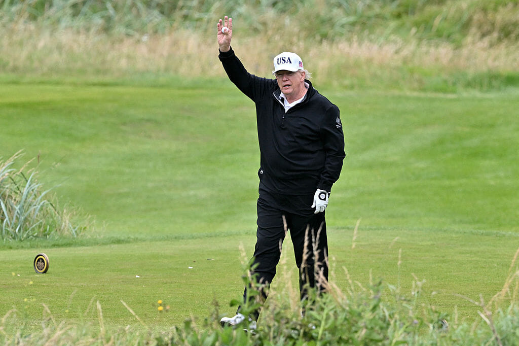 US President Donald Trump reacts as he plays golf.
