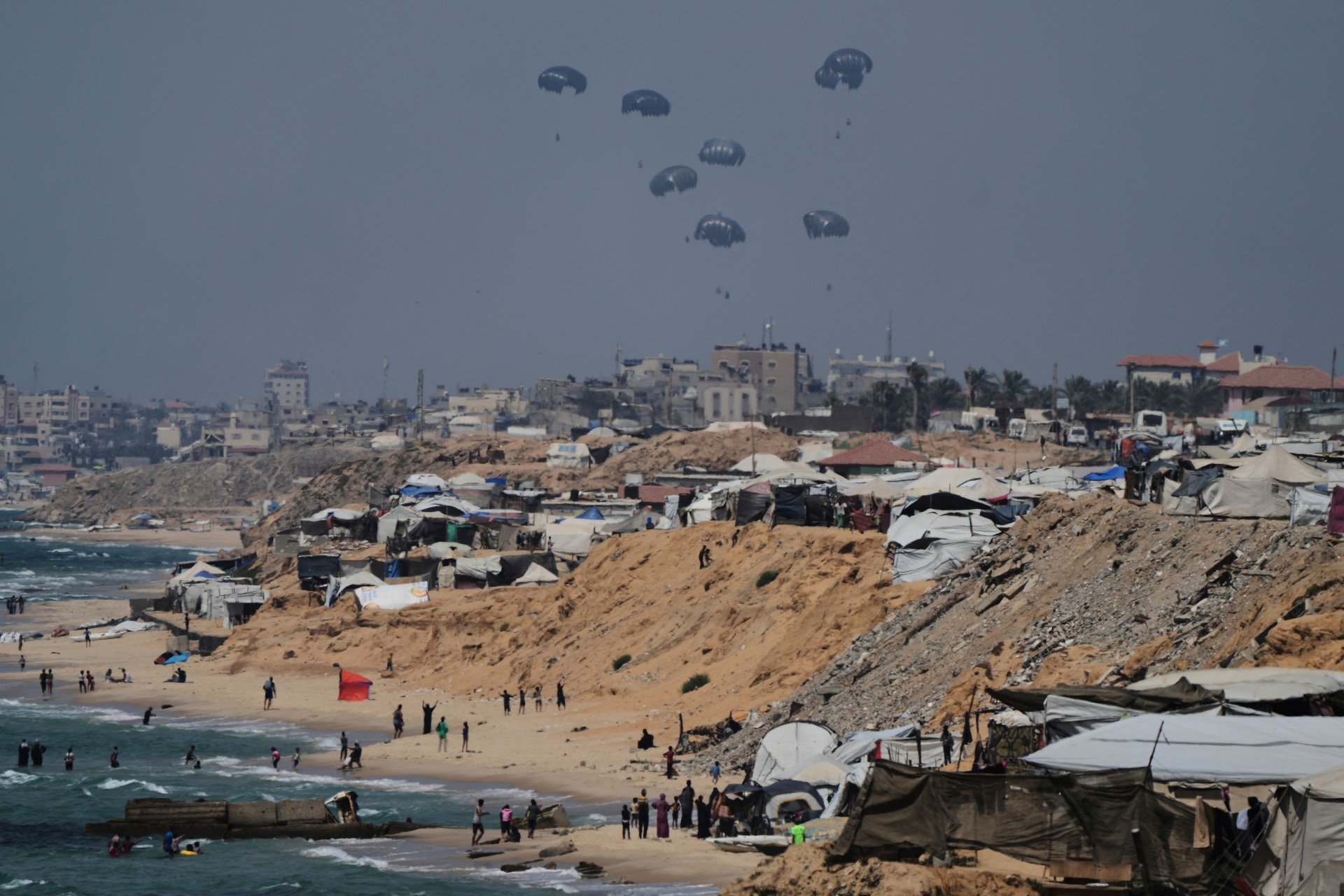 Humanitarian aid is airdropped to Palestinians over the central Gaza Strip as seen from Khan Younis (Abdel Kareem Hana/AP).