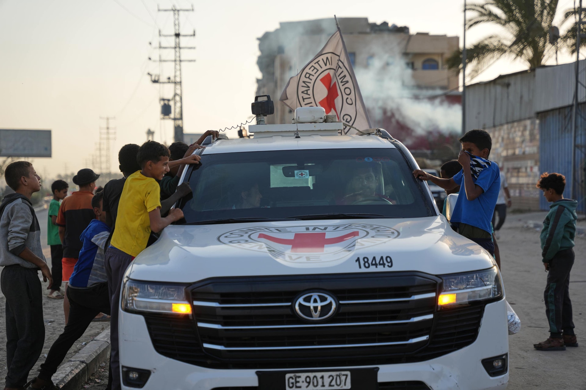 Palestinian children look into a Red Cross vehicle carrying the bodies of two people believed to be deceased hostages handed over by Hamas as it makes its way towards the Kissufim border crossing with Israel in Deir al-Balah, central Gaza Strip