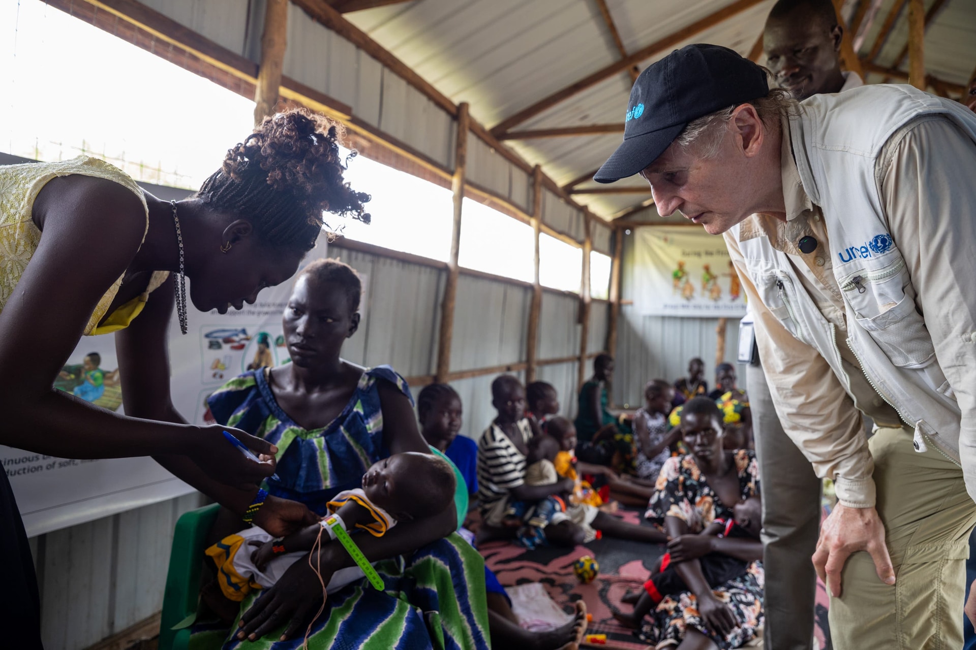 Liam Neeson looks on as six-month-old Gai Malith has his mid-upper arm circumference measured to screen for malnutrition, while held by his mother, Nyang Majok at at the Unicef-supported Kolnyang Primary Health Care Centre in Bor, South Sudan (Unicef/PA).