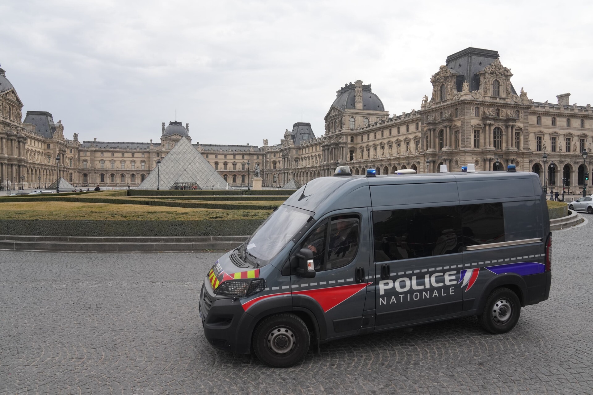 A police van patrols in the courtyard of the closed Louvre museum.