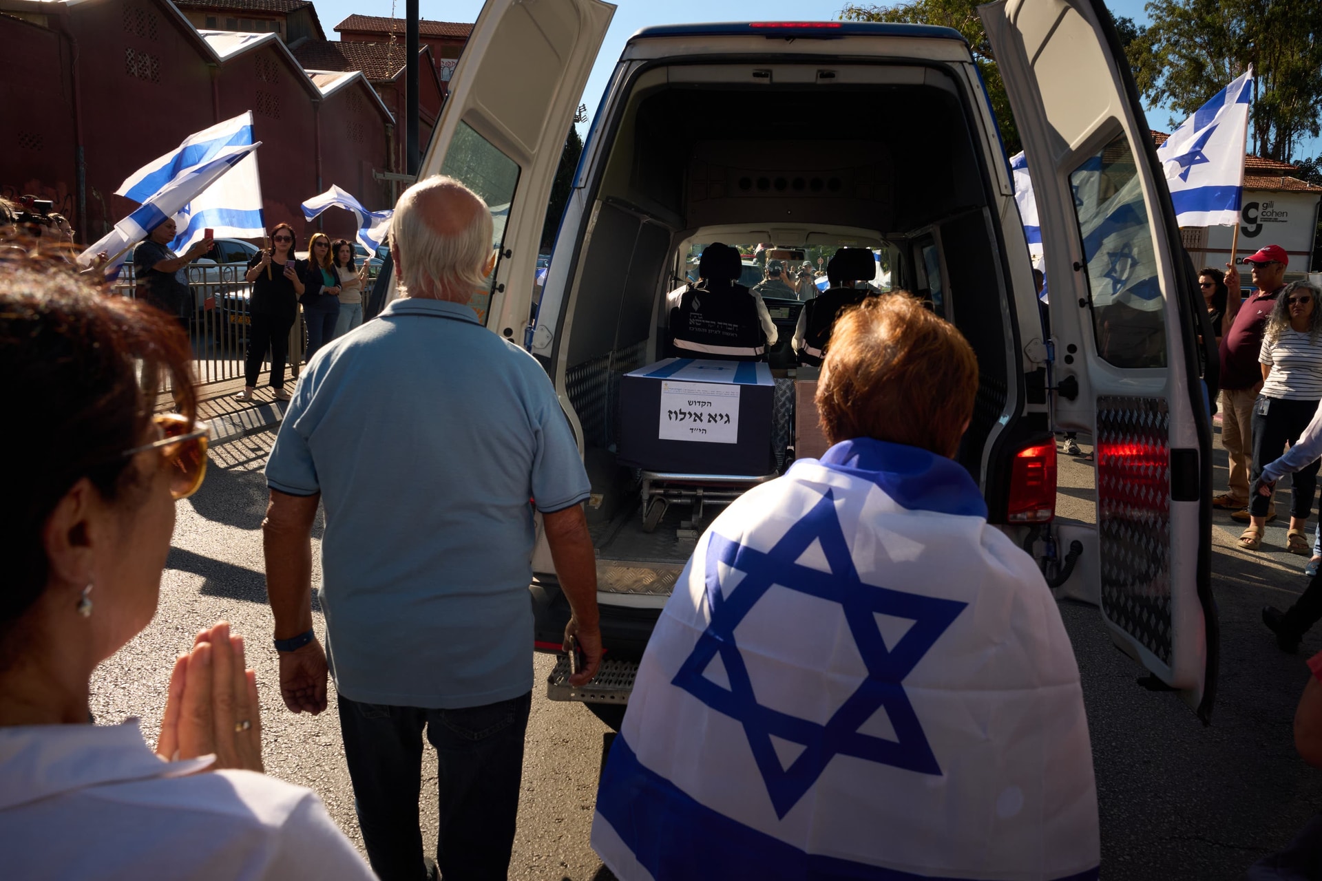 Mourners walk near the car carrying the coffin of a hostage during a funeral procession in Israel (Emilio Morenatti/AP).