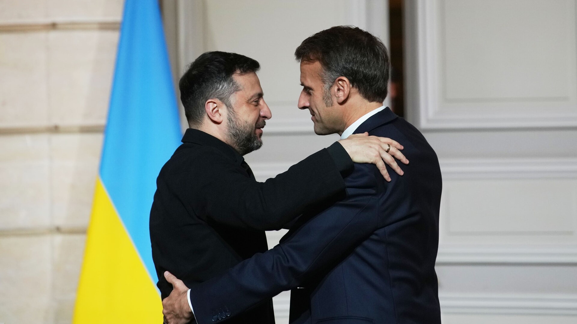 Volodymyr Zelensky and Emmanuel Macron embrace after a joint press conference.