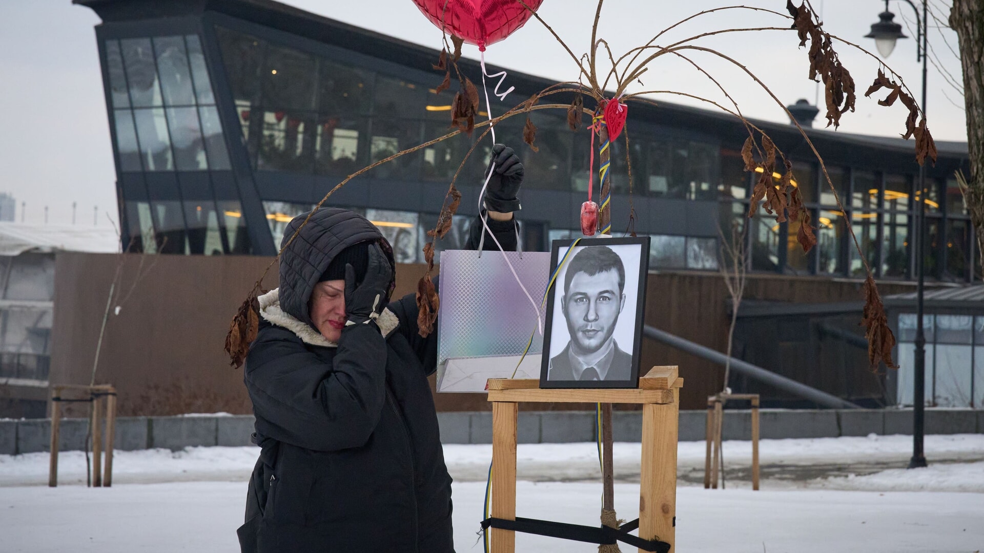 A woman wipes tears next to a photo of a fallen soldier on ‘Love Alley’, created in Kyiv in honour of sons and husbands killed in the war