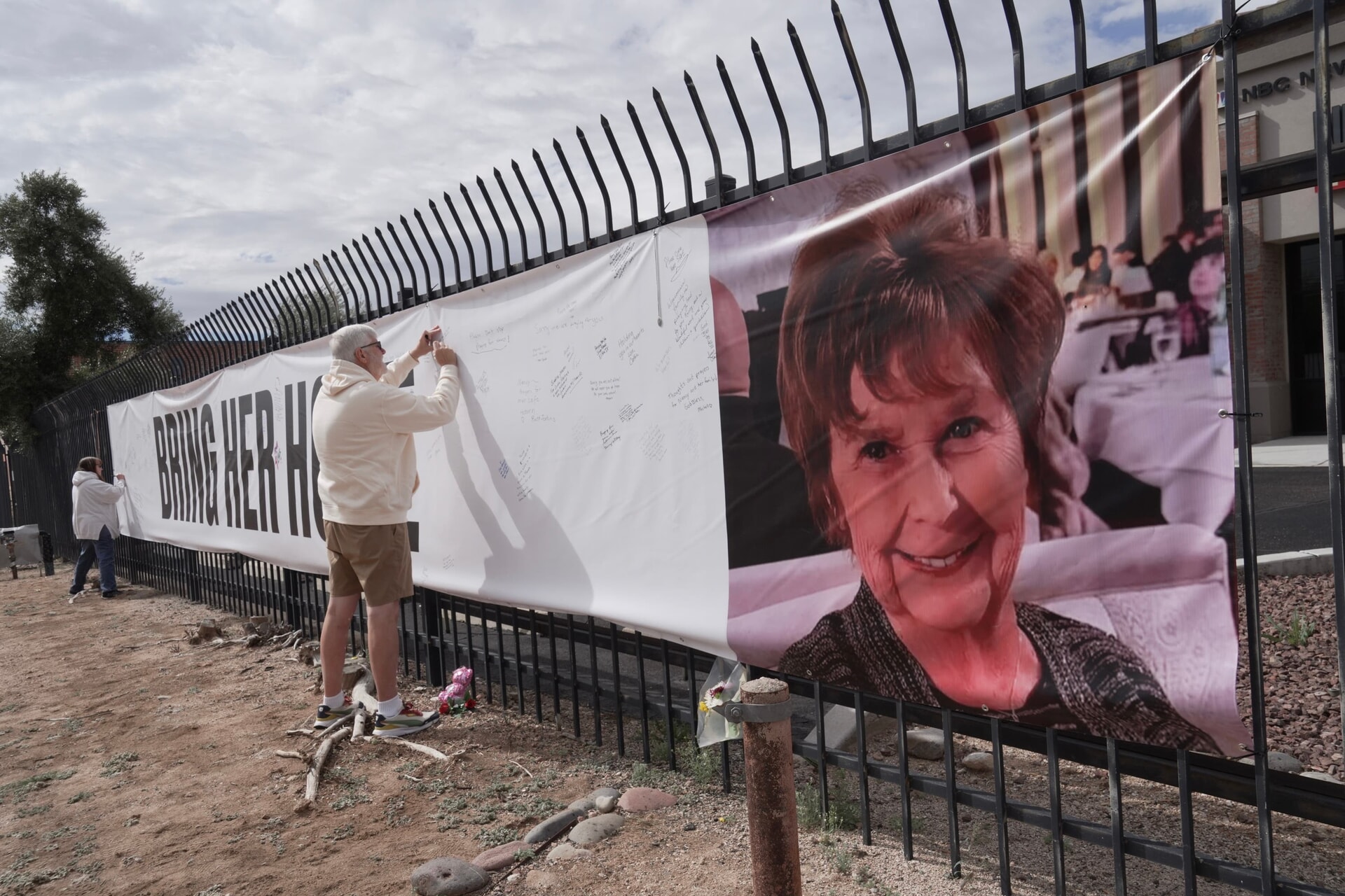 A man signs a banner calling for Nancy Guthrie’s return.