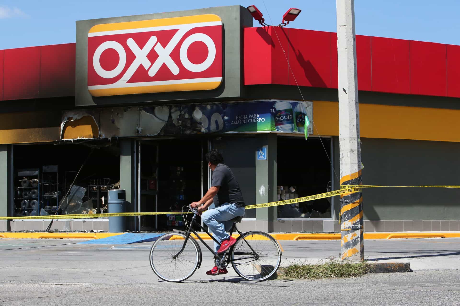 A man rides a bike next to a convenience store that was set on fire, in San Francisco del Ricon, Guanajuato state, Mexico
