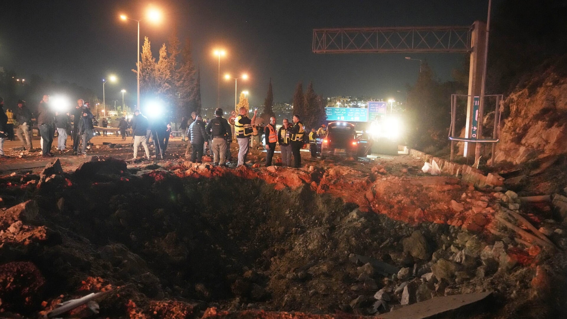 Israeli security forces inspect a damaged road after a missile launched from Iran struck Jerusalem on Sunday
