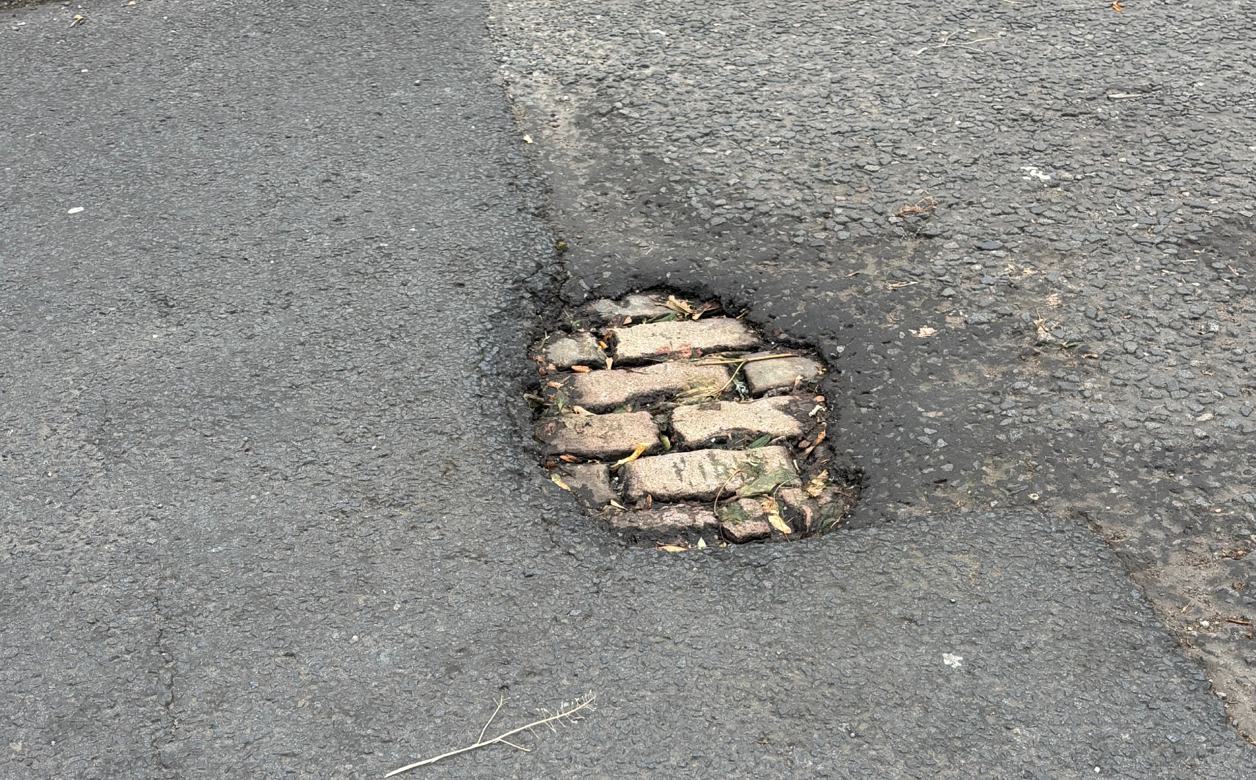 A pothole reveals cobblestones on Midlock Street, Glasgow.
