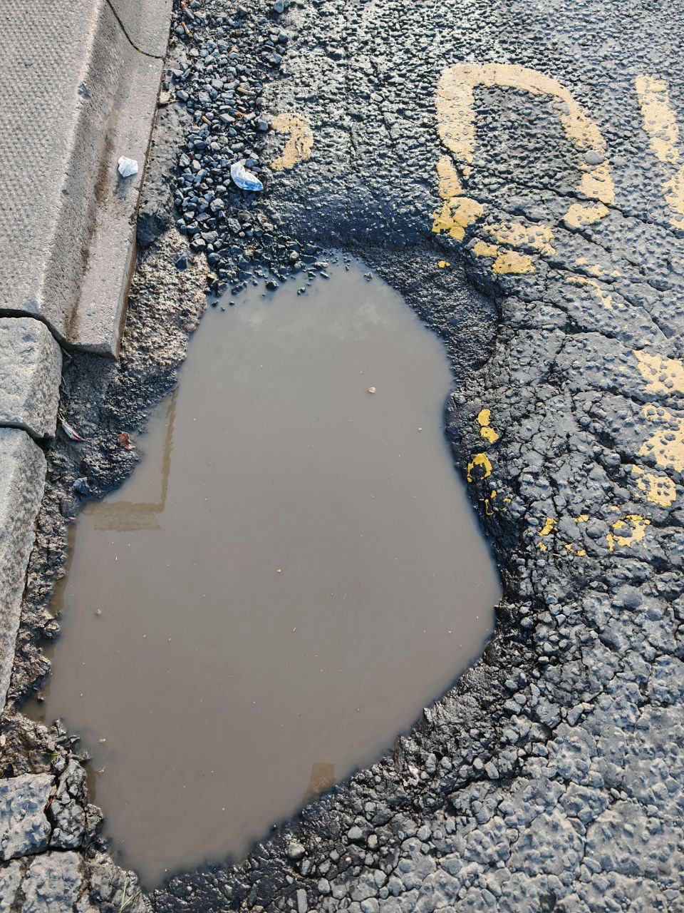 Pothole at bus stop on Paisley Road West in Glasgow.
