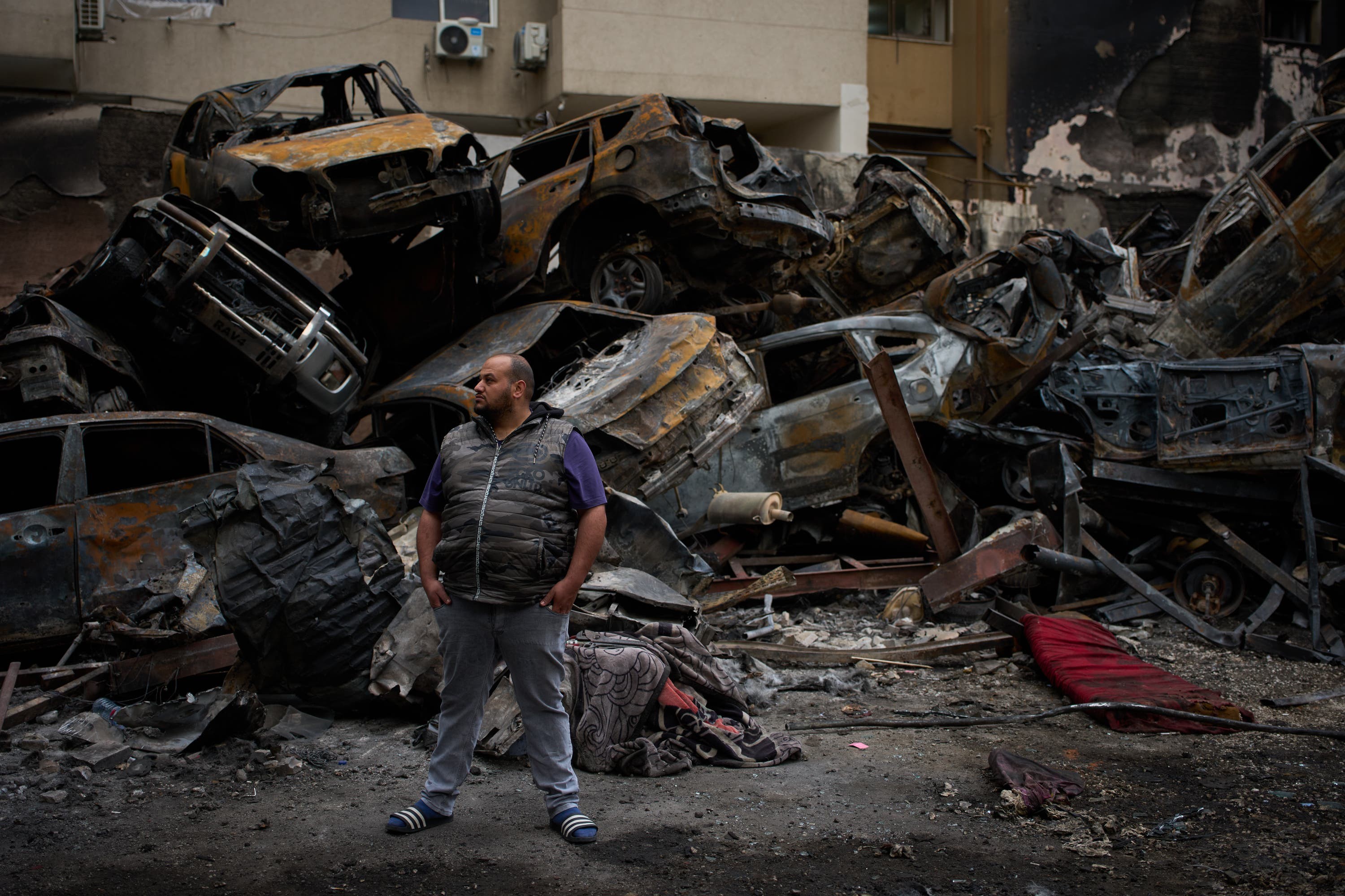 A man stands in front of charred cars at the site of Wednesday’s Israeli air strike in Beirut