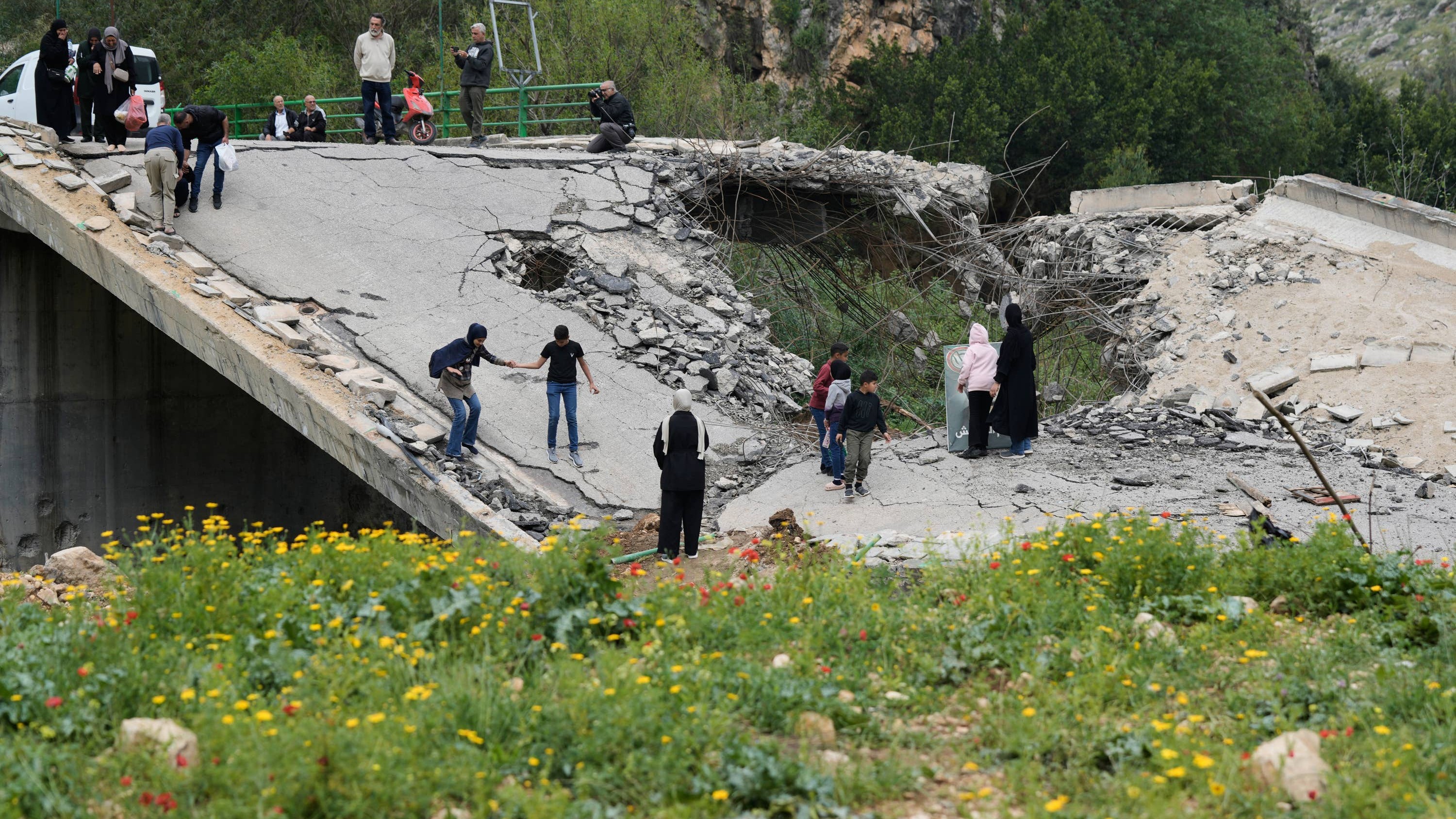 Displaced people cross a destroyed bridge as they return to their villages following a ceasefire between Hezbollah and Israel, in Tayr Felsay village, Lebanon