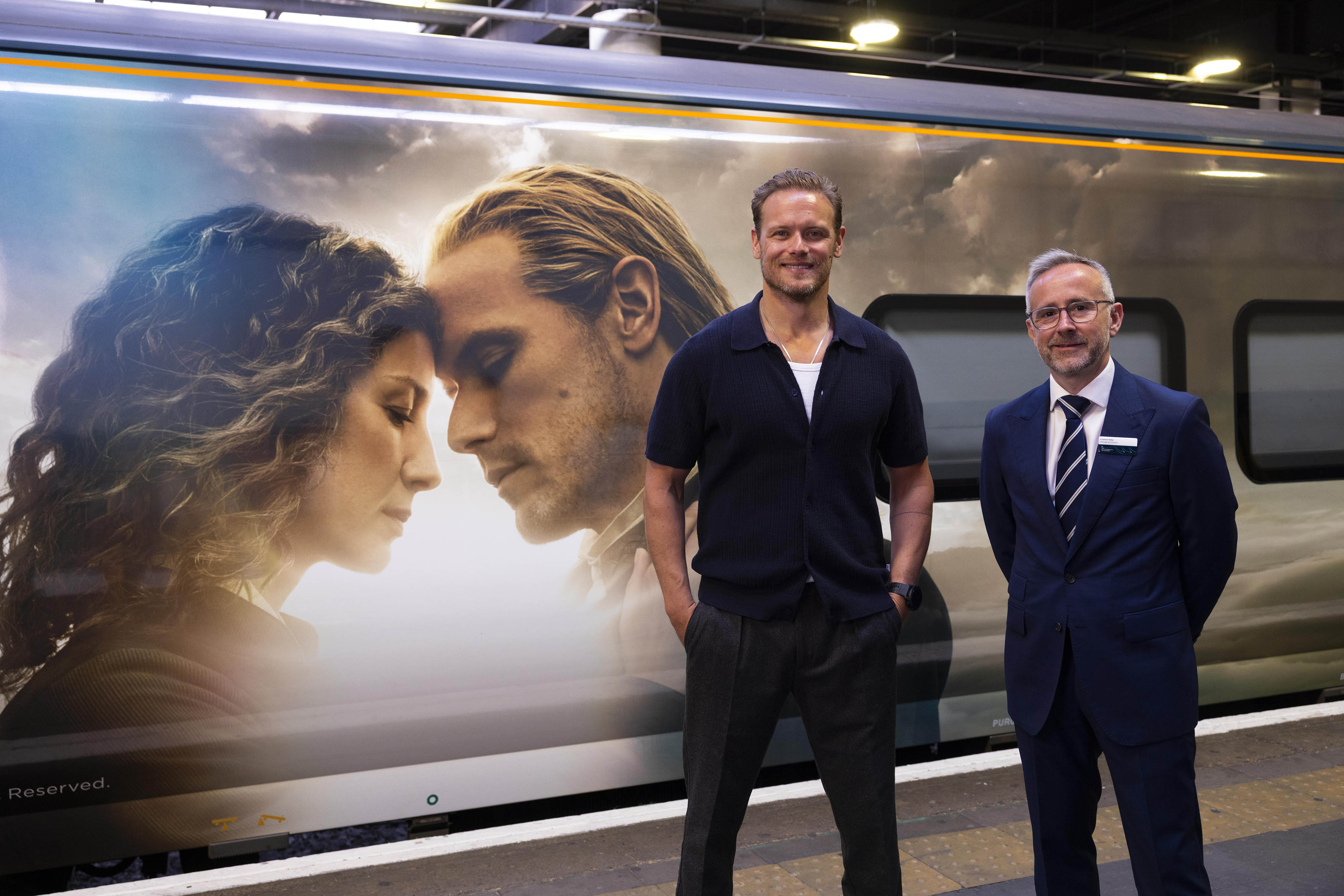 Sam Heughan (left) and Graham Kelly, managing director, Caledonian Sleeper unveil the Caledonian Sleeper's first full train wrap in London's Euston station.