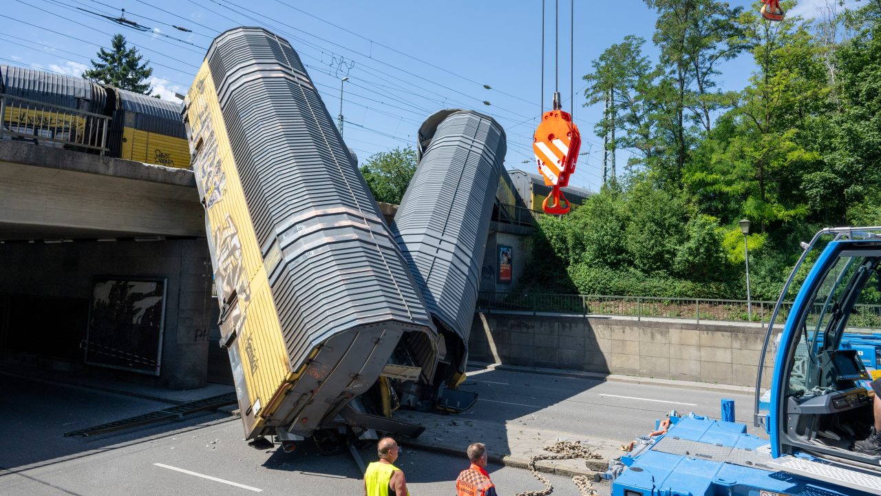 One dead as freight train goods wagons plunge off bridge