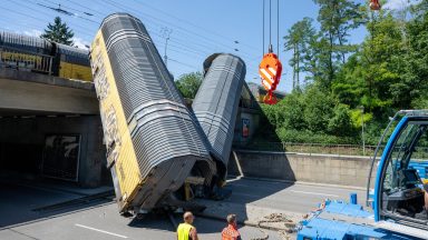 One dead as freight train goods wagons plunge off bridge